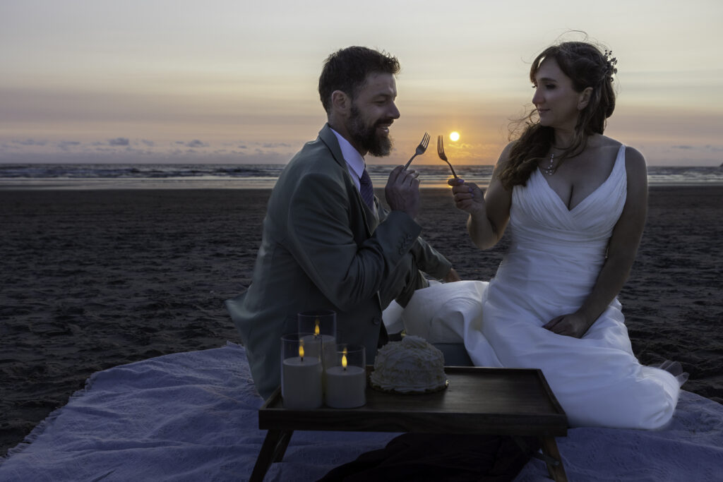 couple sharing their cake at sunset clink forks together