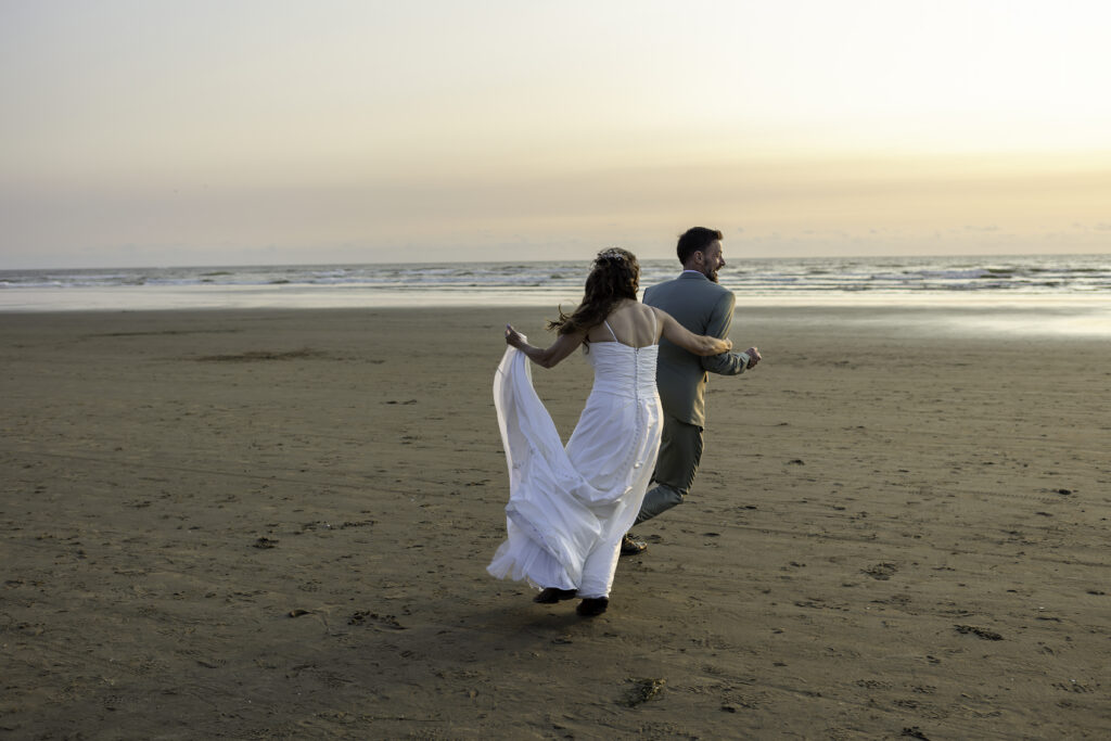wedding couple play a vigorous game of tag on the beach 