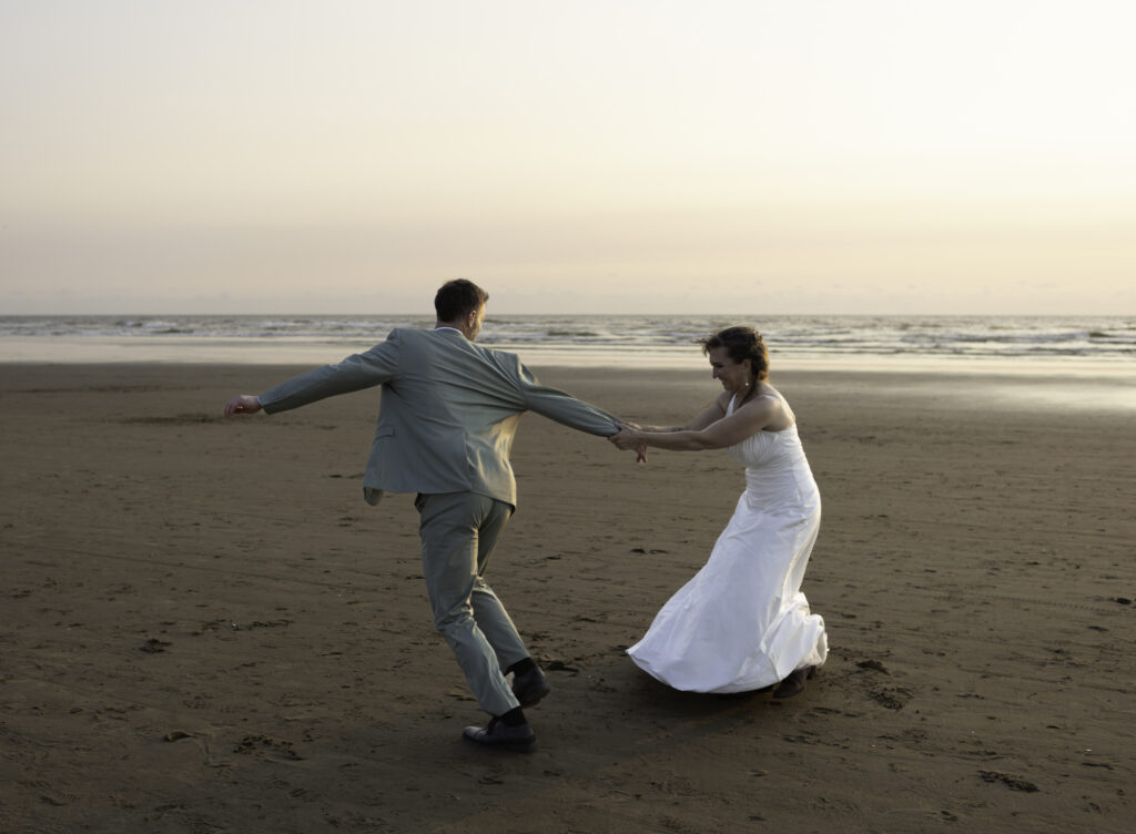 wedding couple play a vigorous game of tag on the beach