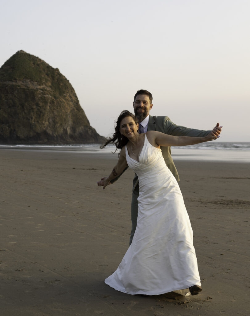 Couple standing with man in back and woman in front with airplane arms pose