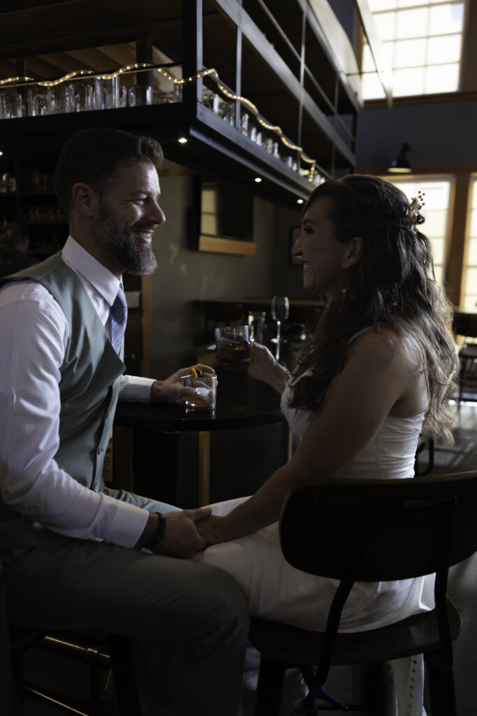 wedding couple at Pelican Brewery bar holding hands and looking at each other while holding their drinks