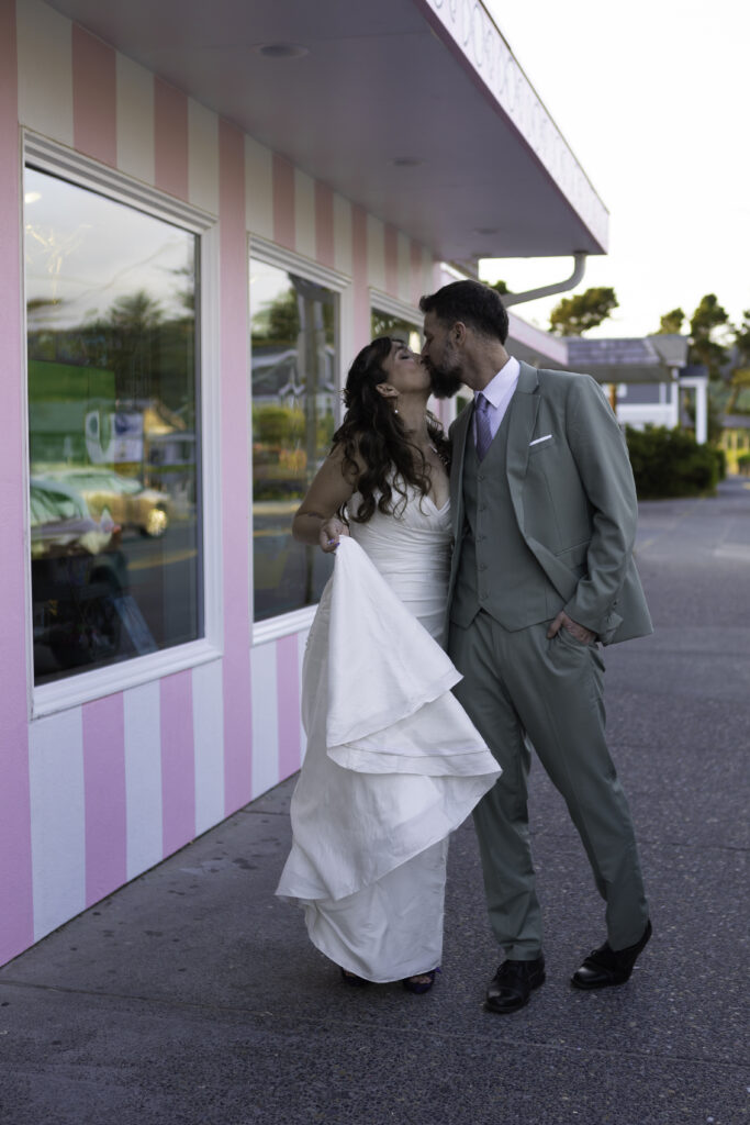 couple walks hand and hand down the charming streets of cannon beach oregon and stop for a kiss