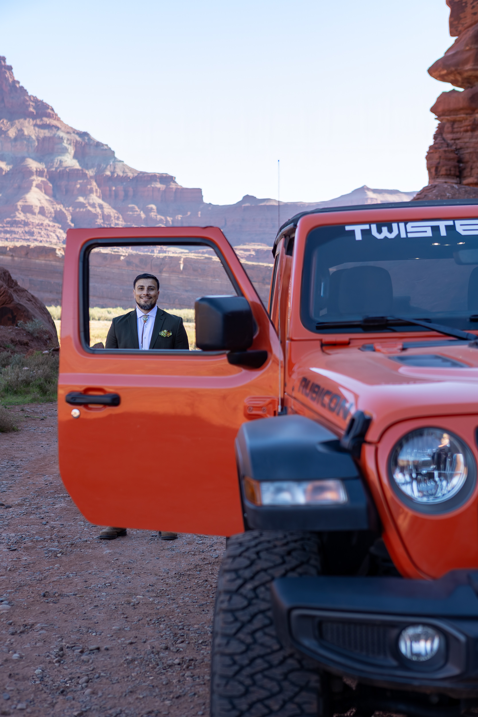 fun picture of hugo standing in cut out of window of open jeep door with moab scenery in background
