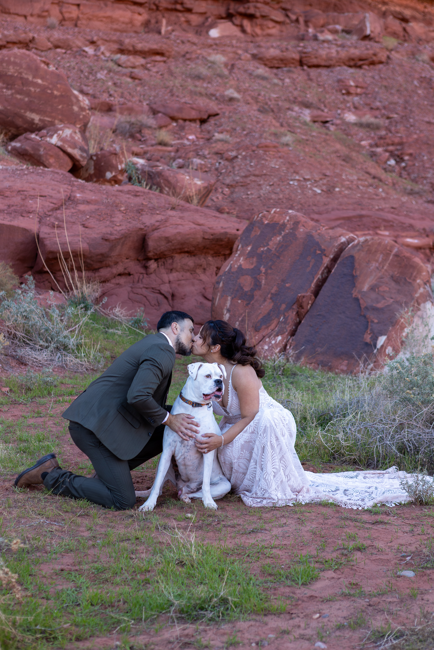 Laura and Hugo kiss while holding their dog hugo between them 
