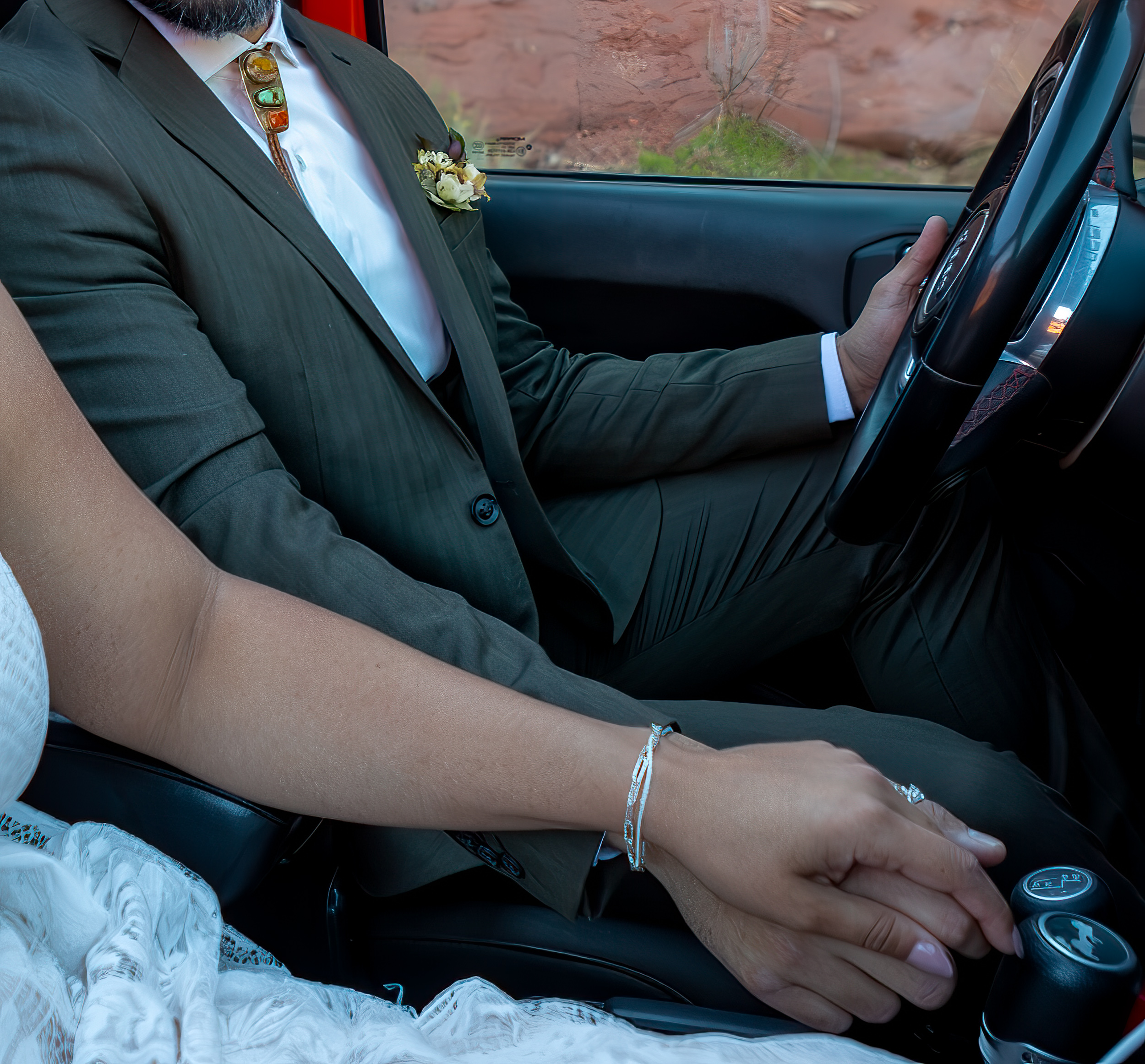 couple hold hands as they drive in a jeep on their wedding day