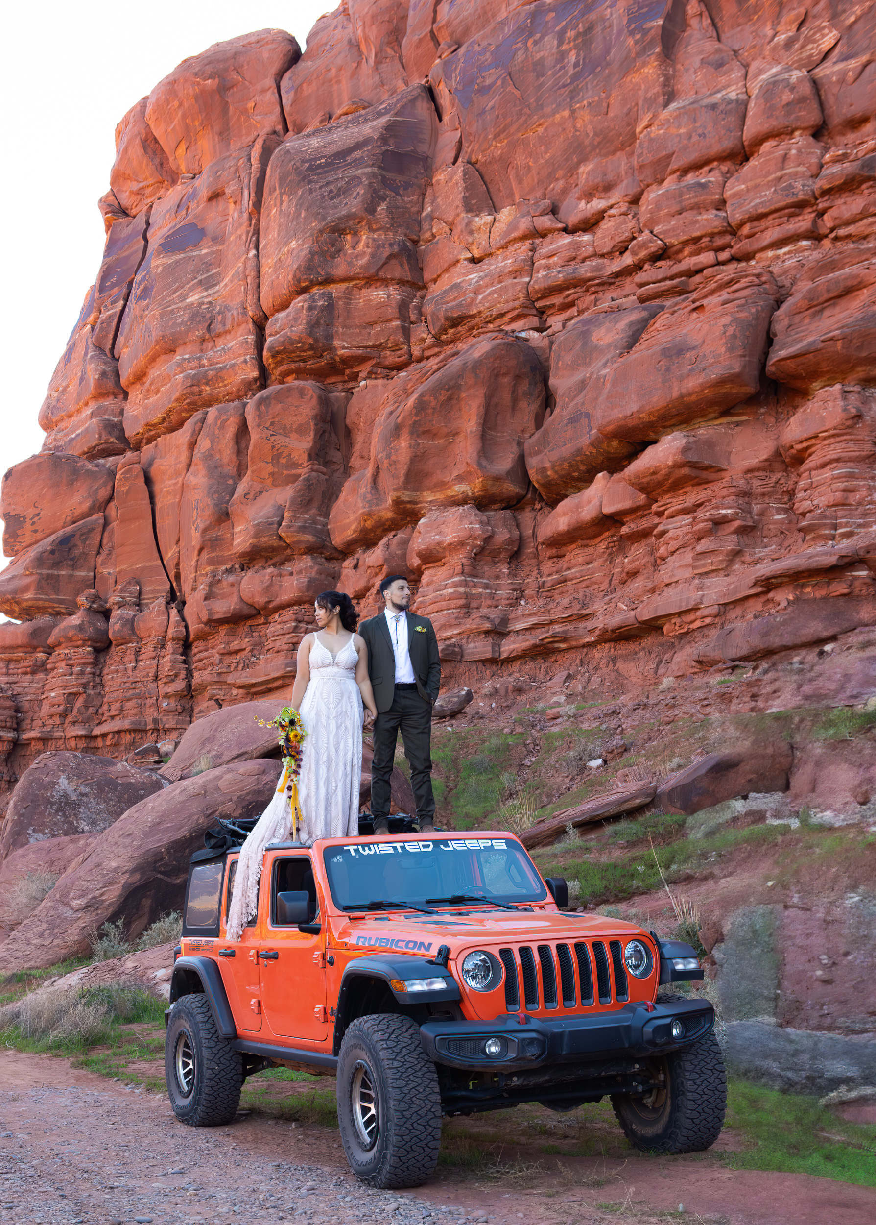 Hugo and Laura stand dramatically on the back of the jeep