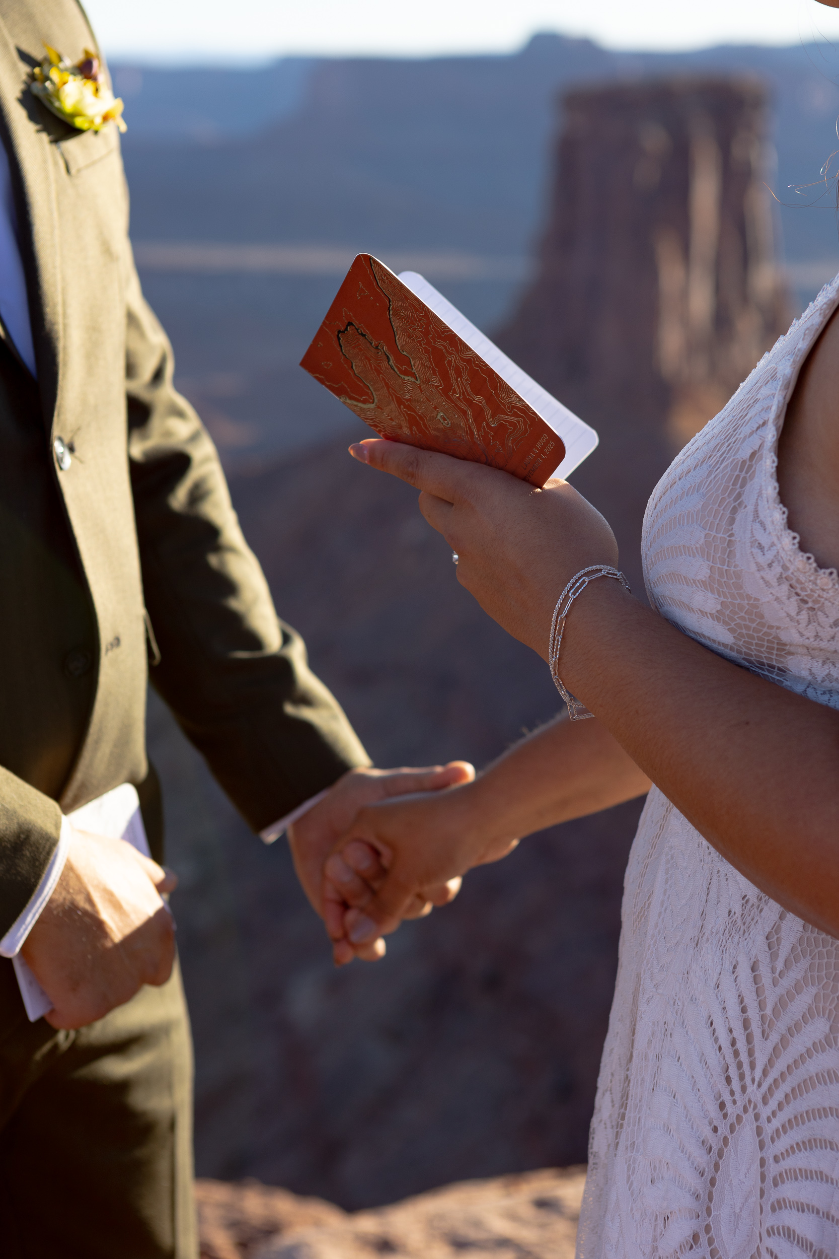 close up of the vow book and couple holding hands