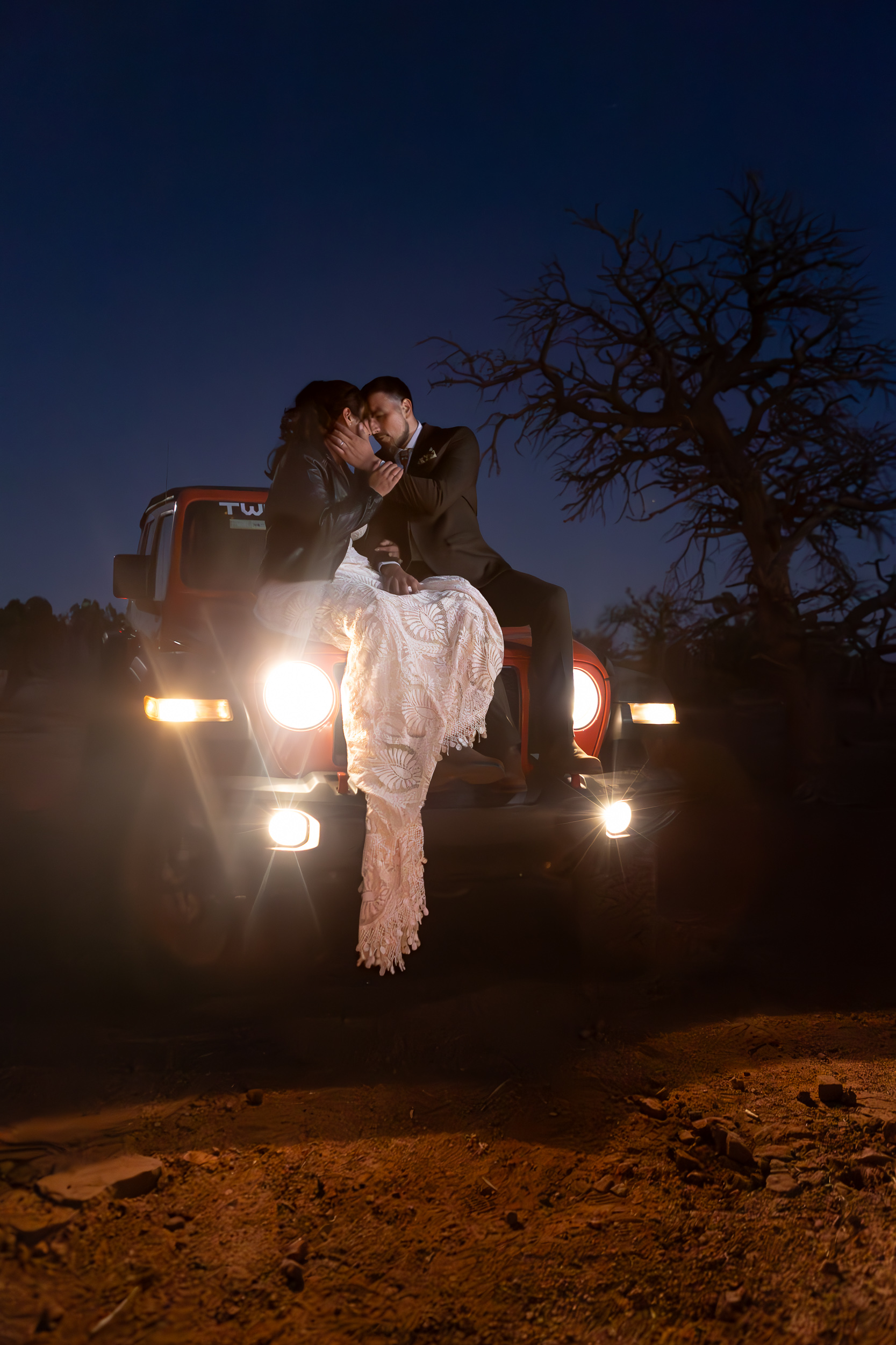 couple embracing and kissing on the hood of their jeep during their moab elopement