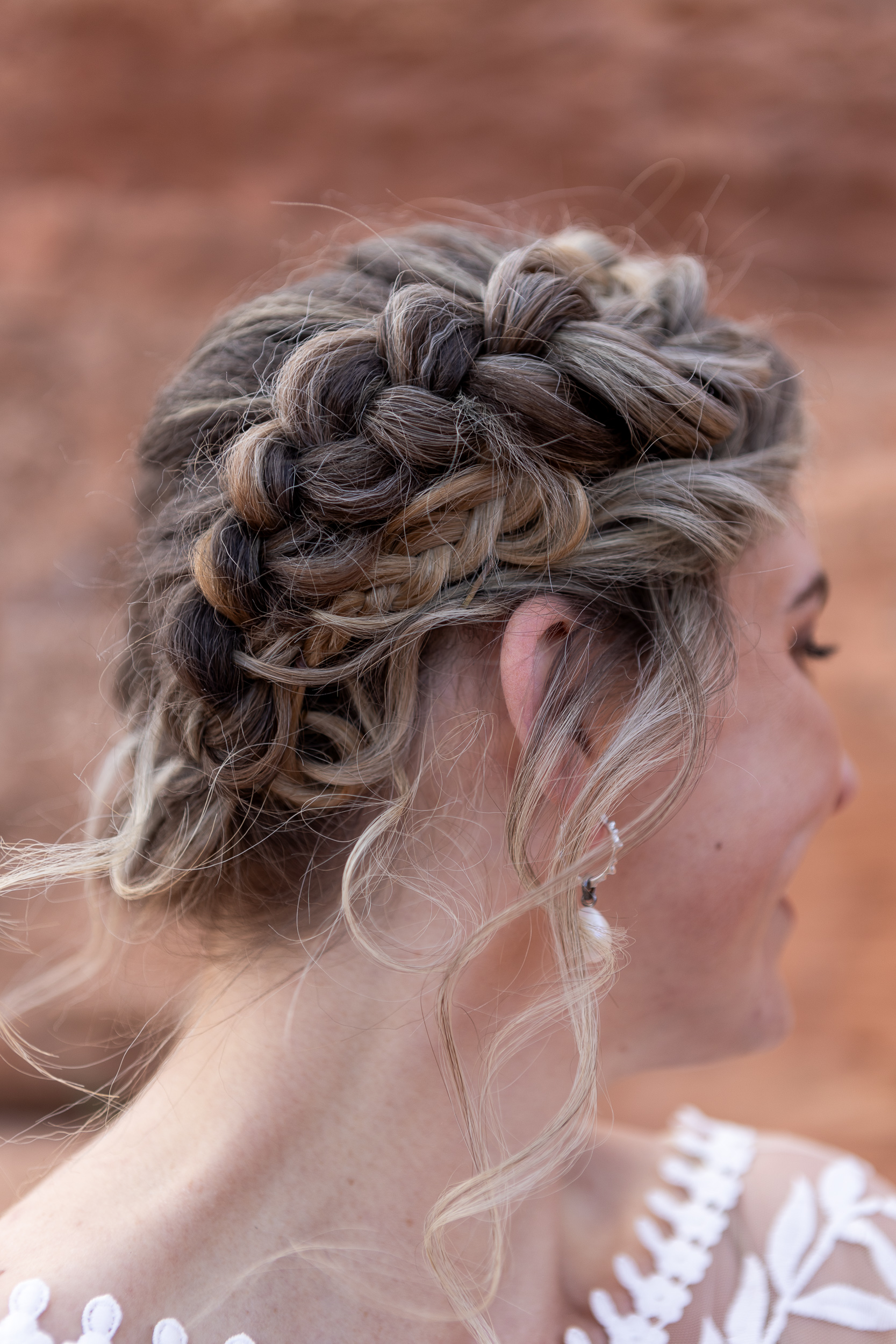 bride sitting on the red rocks in moab in wedding dress with floral bouquet on lap