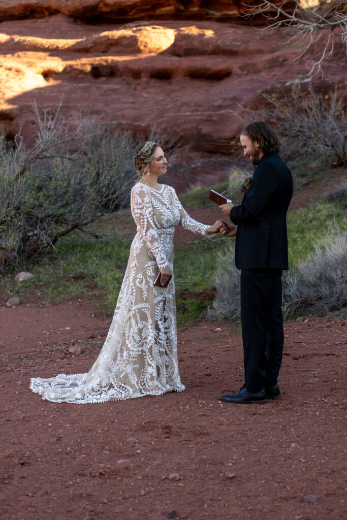 groom reading his vows while holding brides hand