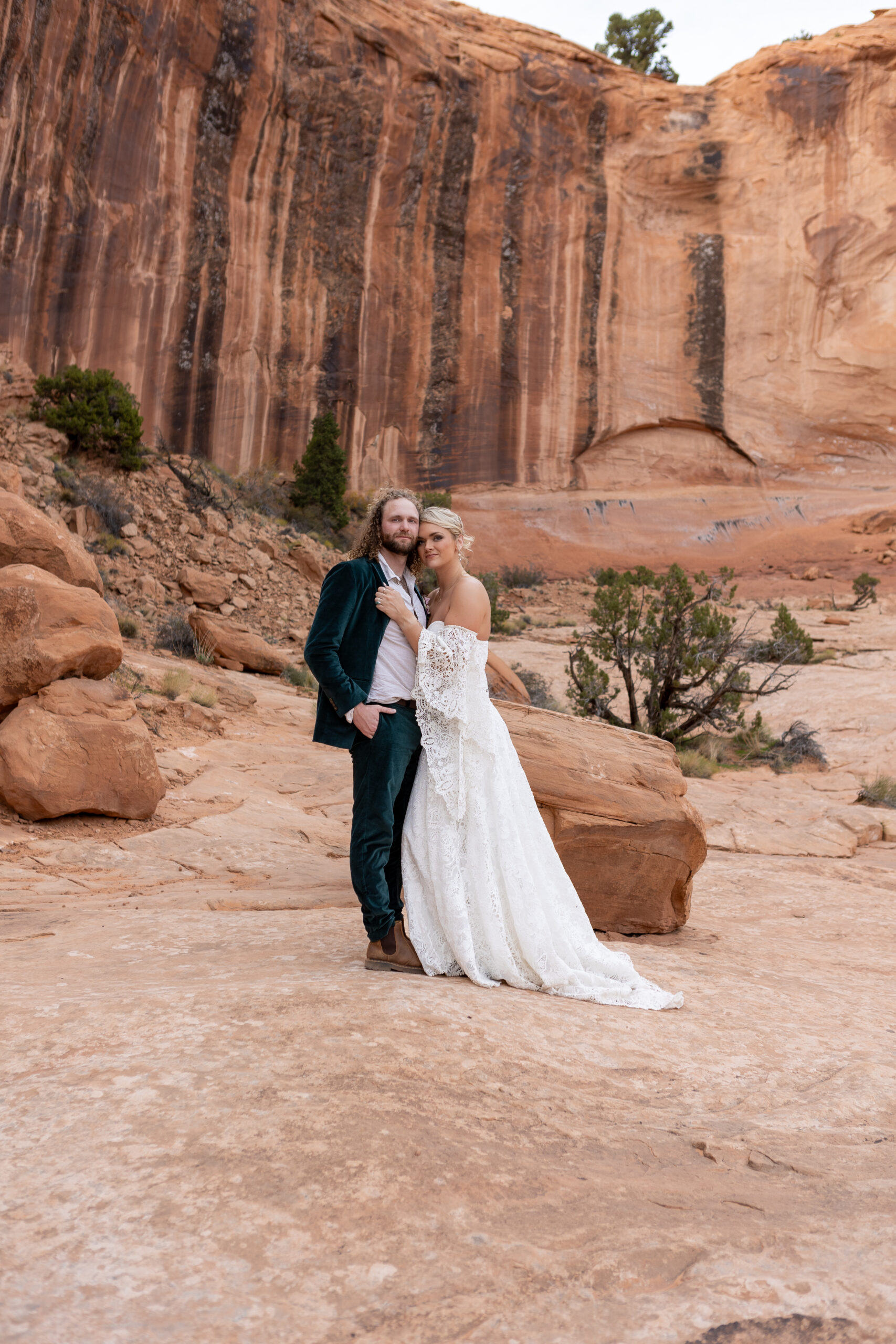 bridal couple embracing chest to chest and heads together looking at camera in moab at Corona Arch