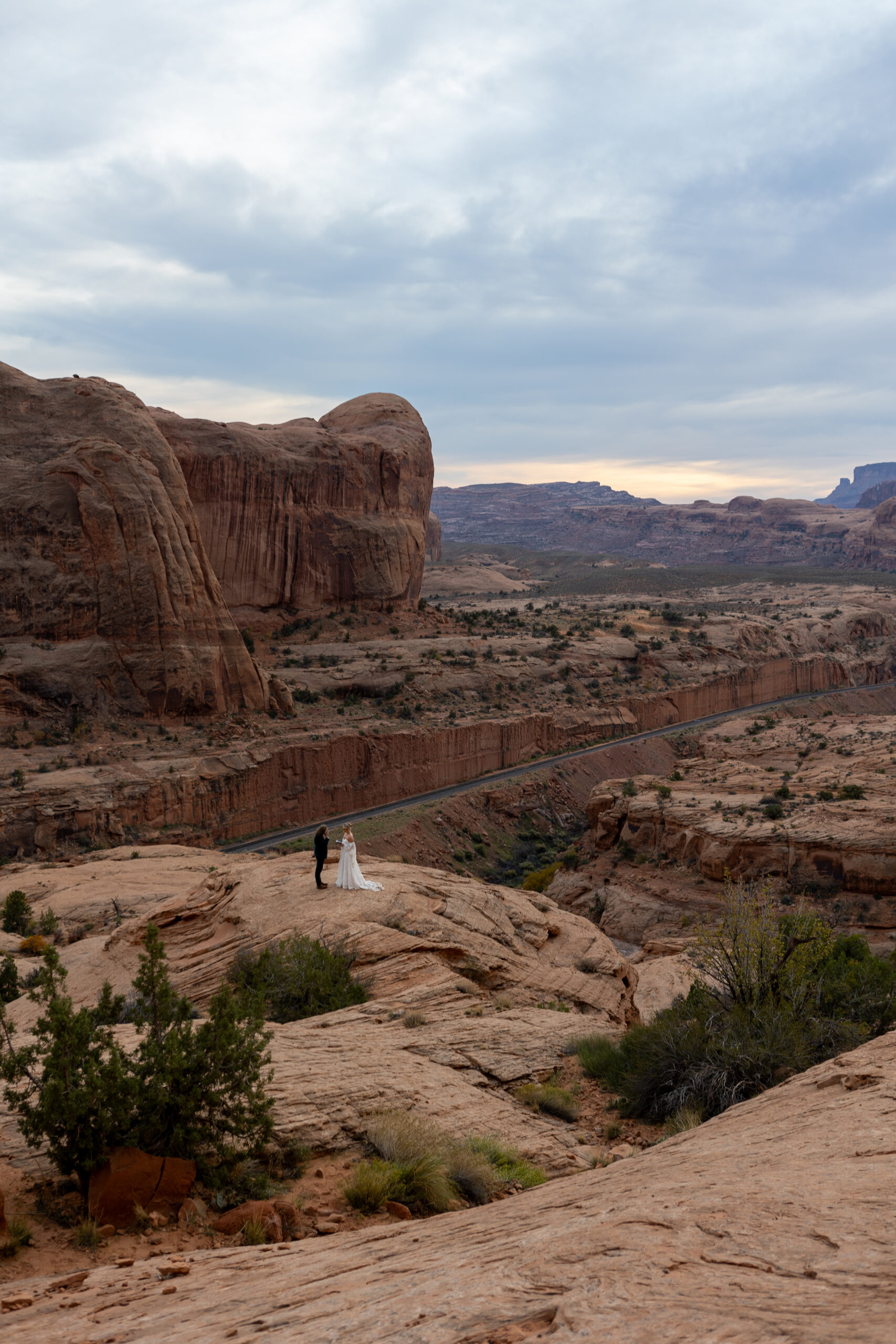 Distant view of a couple privately exchanging vows alone in a remote desert landscape in Moab, Utah