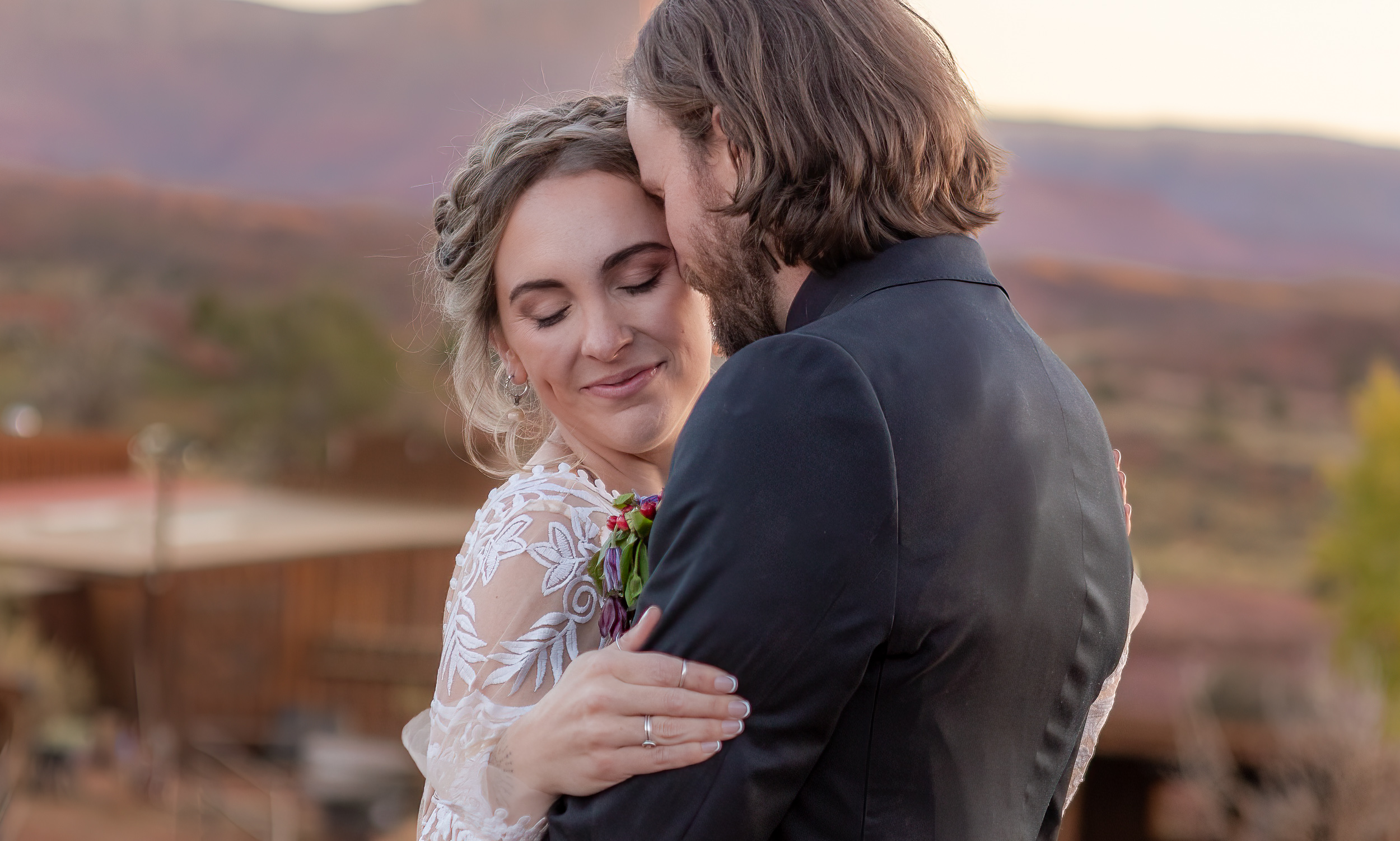 couple embraces during golden hour at a ranch. husband is leaning his forehead against her temple. 