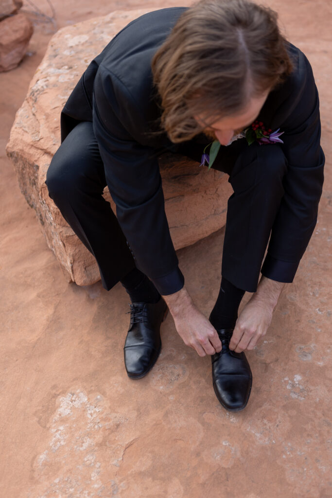 adjusting shoe laces while sitting on a rock