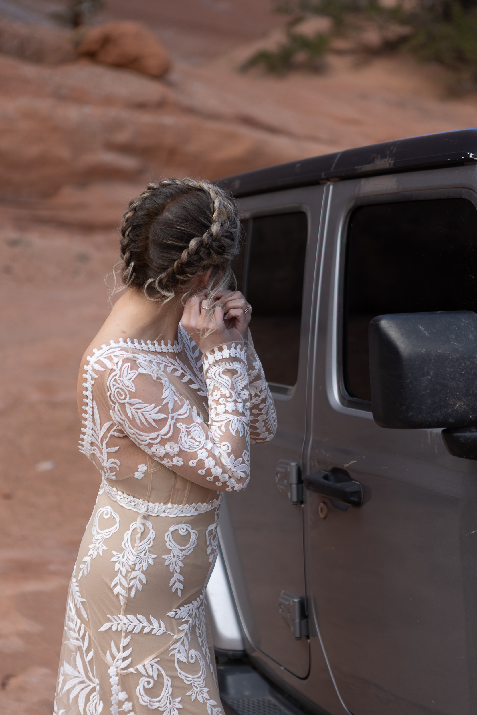 bride adjusting earring in jeep window closer up