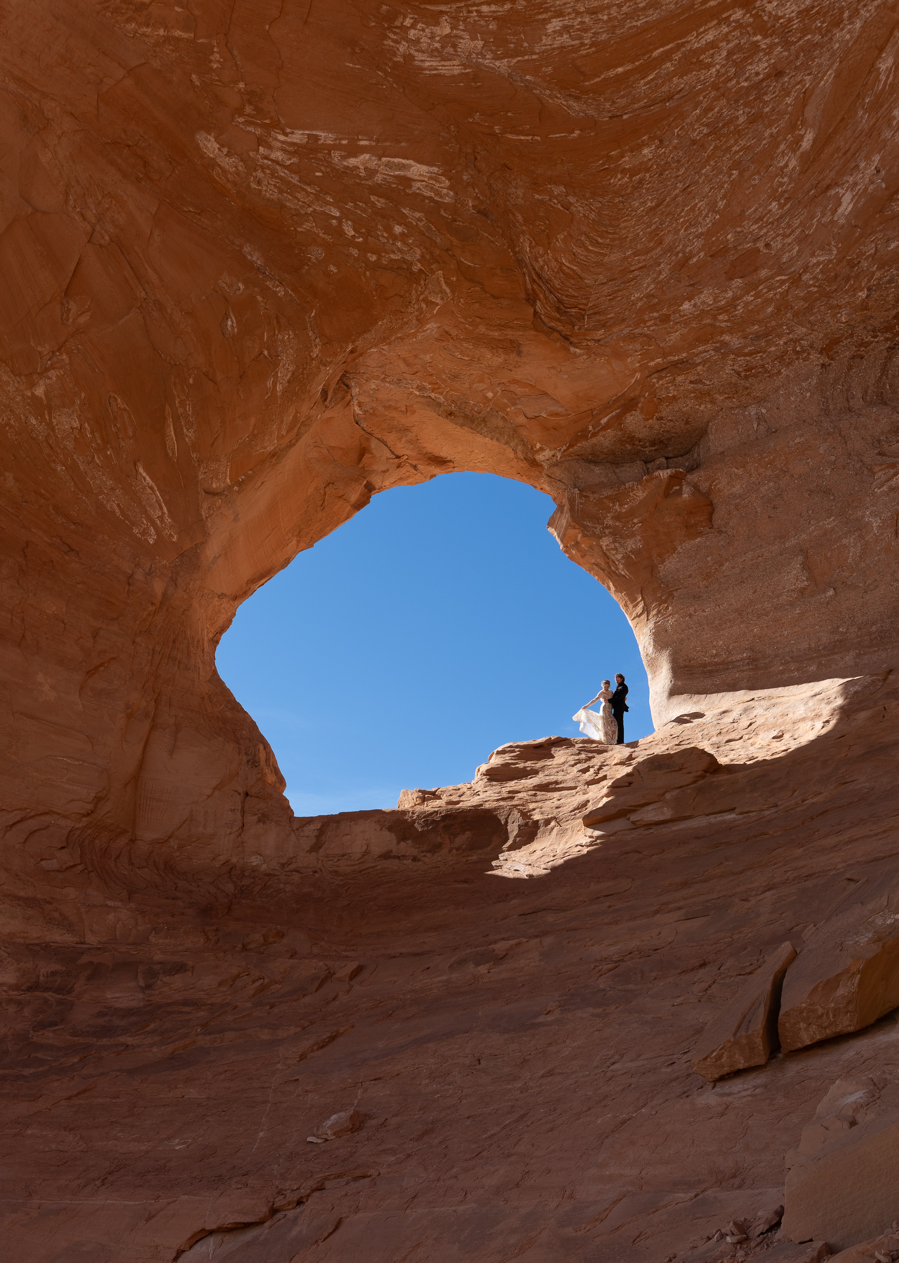 couple posed inside mirror arch