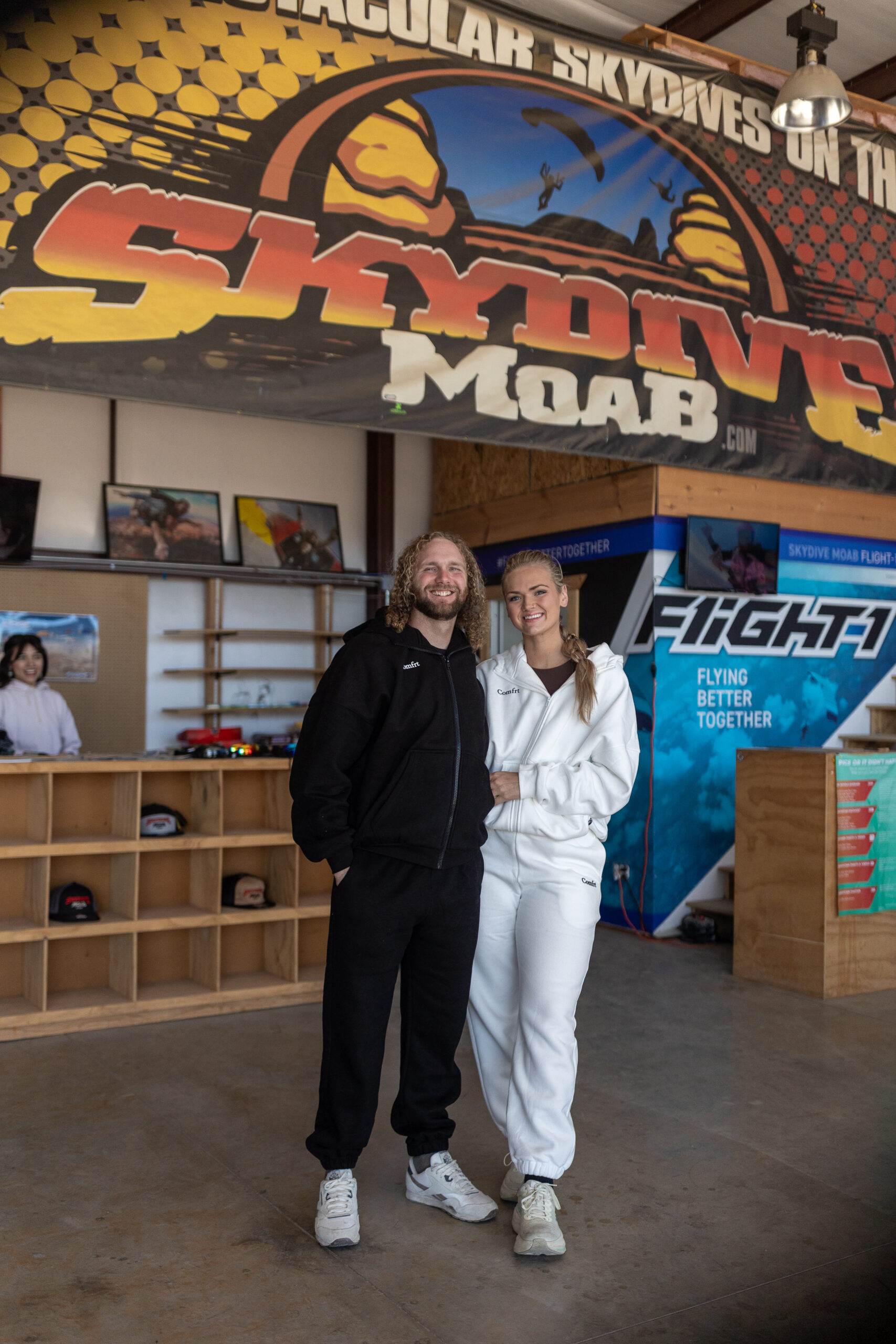 Madison and Isaac preparing for their skydiving elopement in Moab, wearing black and white sweatsuits before their jump