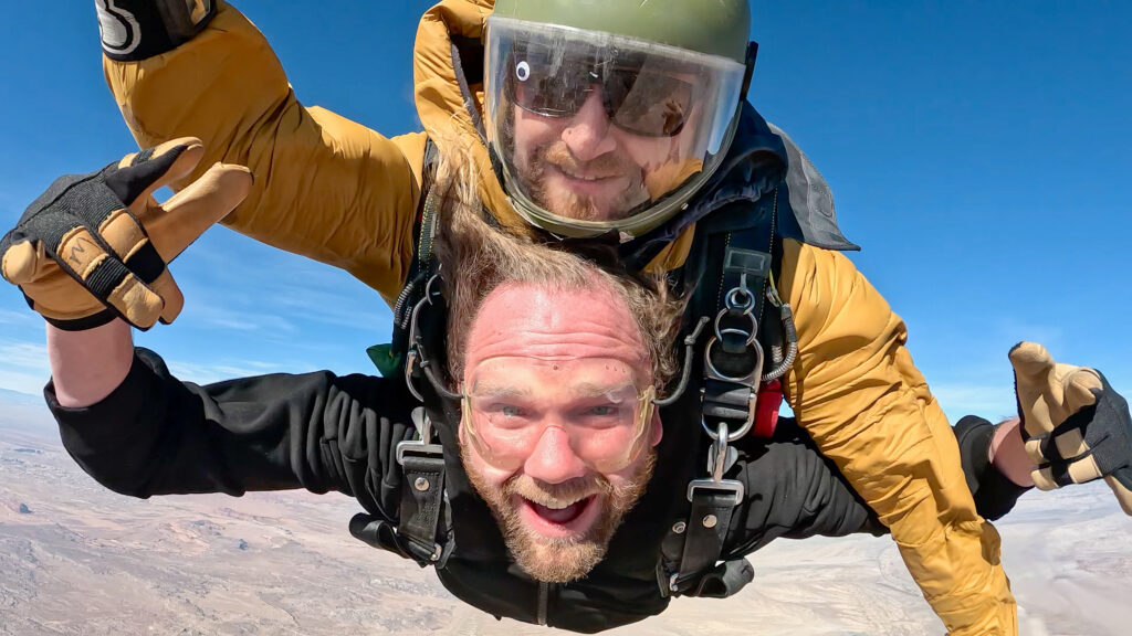 Groom skydiving over Moab, Utah with sweeping views of the desert during an elopement adventure