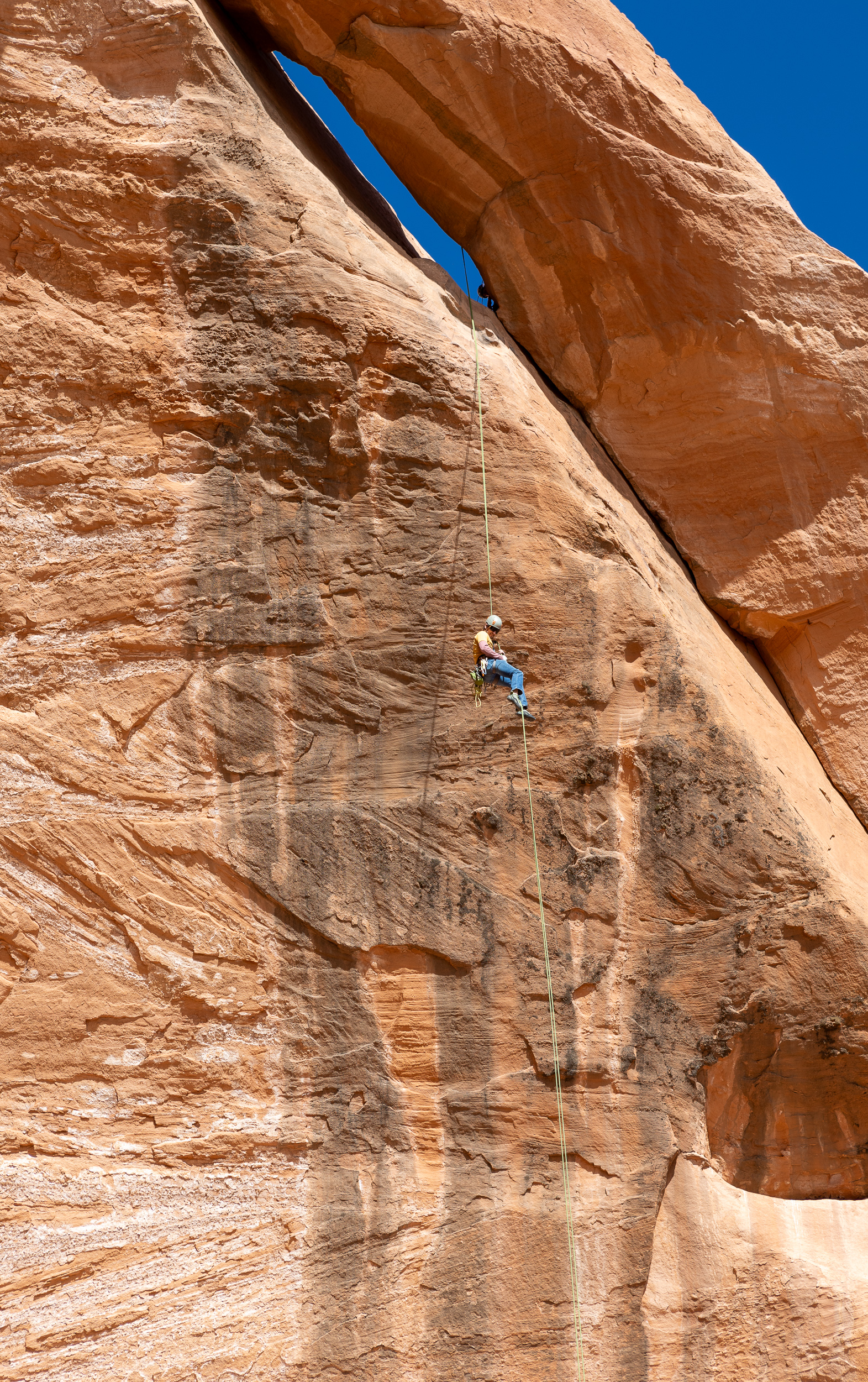rock climber repelling down cliff close up