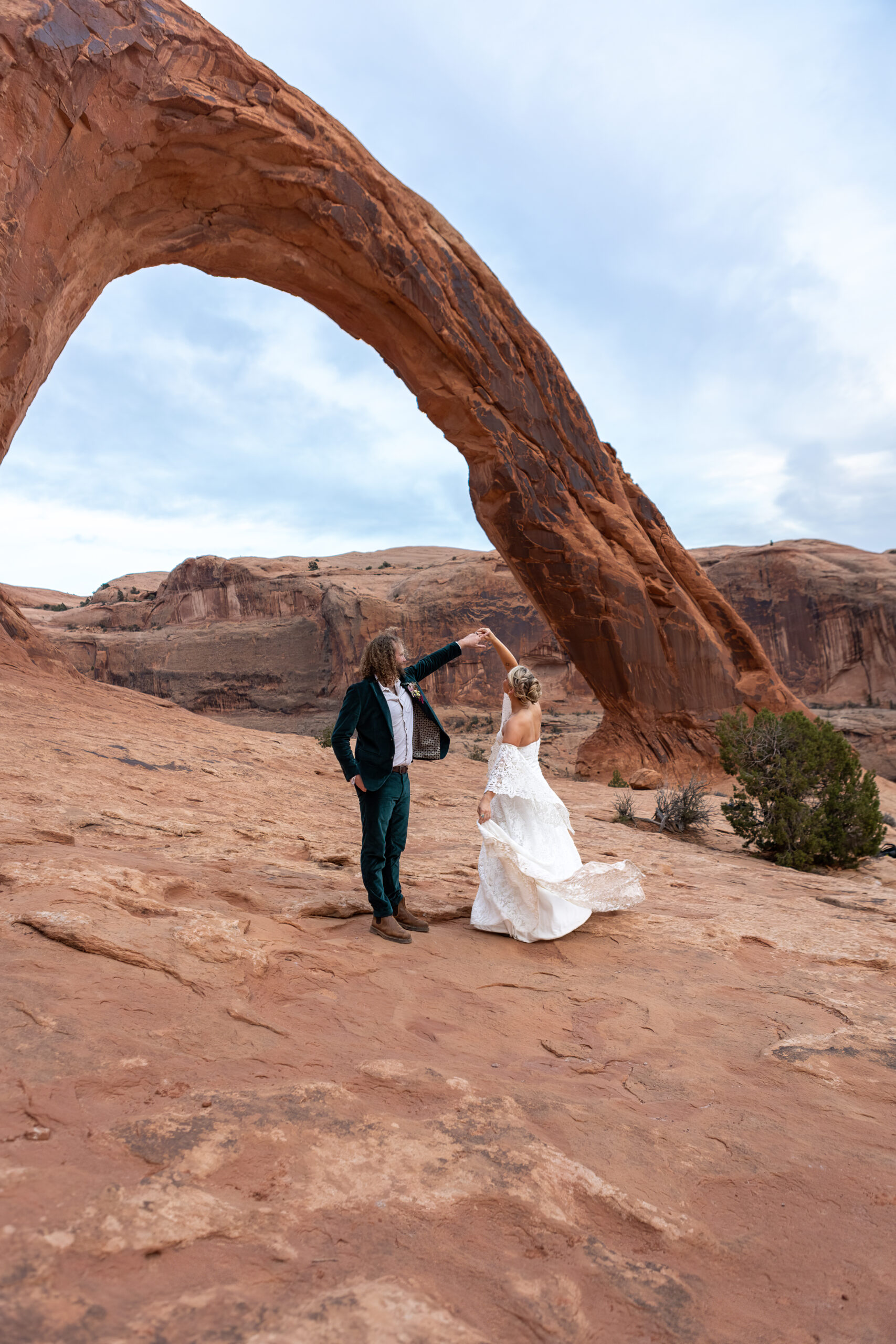 Couple dancing together in front of Corona Arch in Moab, Utah during their elopement session