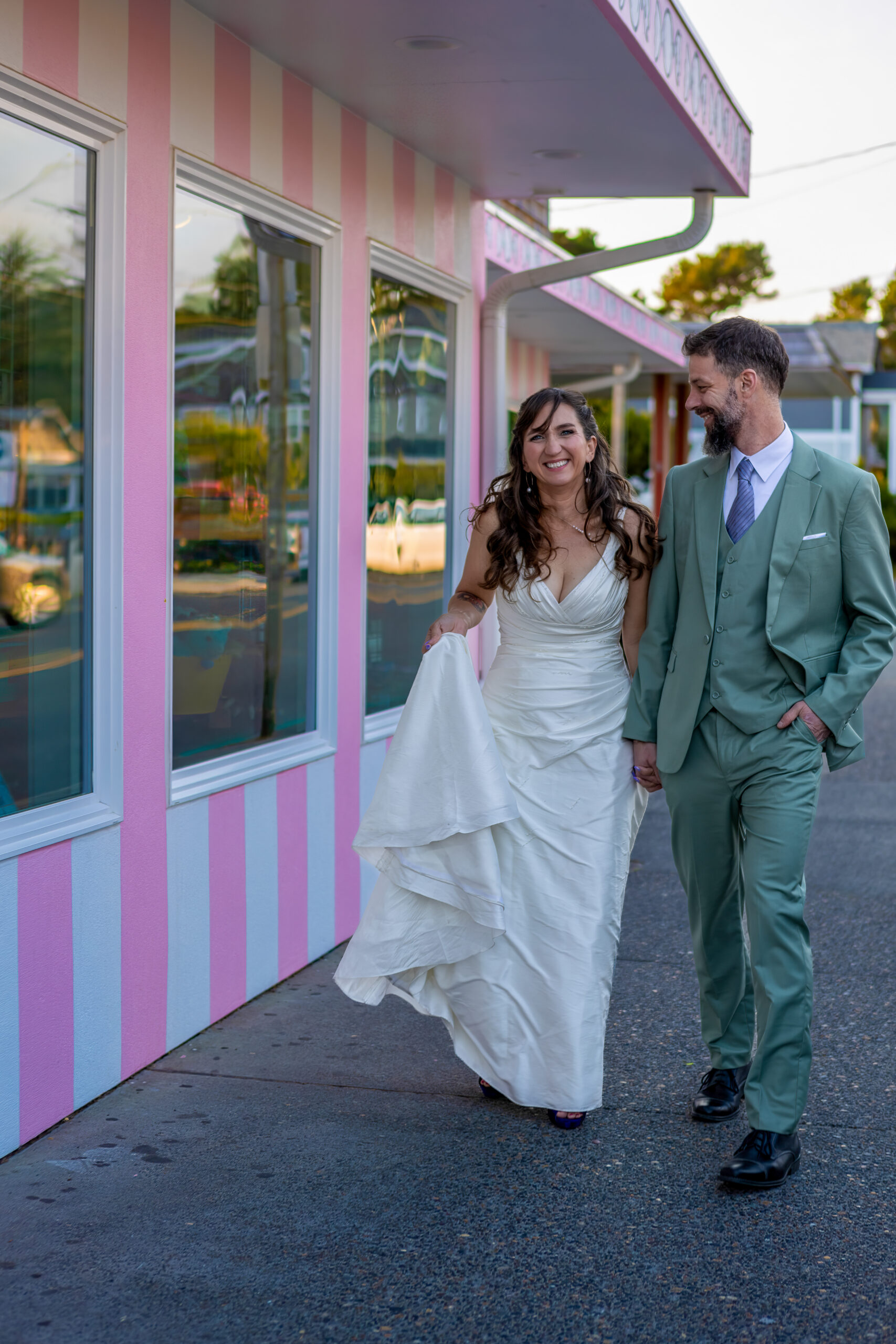 couple walking hand and hand though downtown cannon beach on their elopement day. 