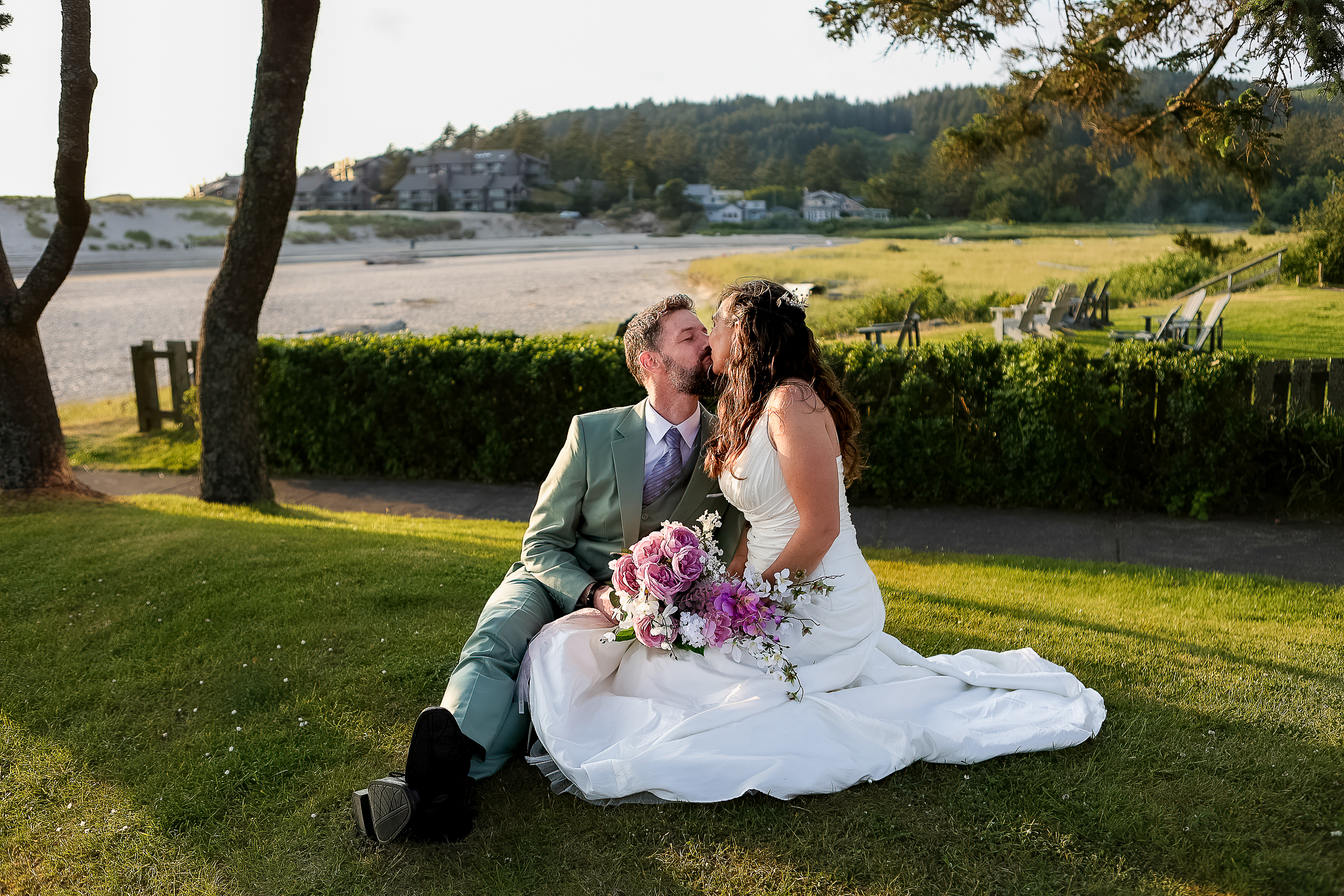 couple kissing on a green grassy spot by the coast