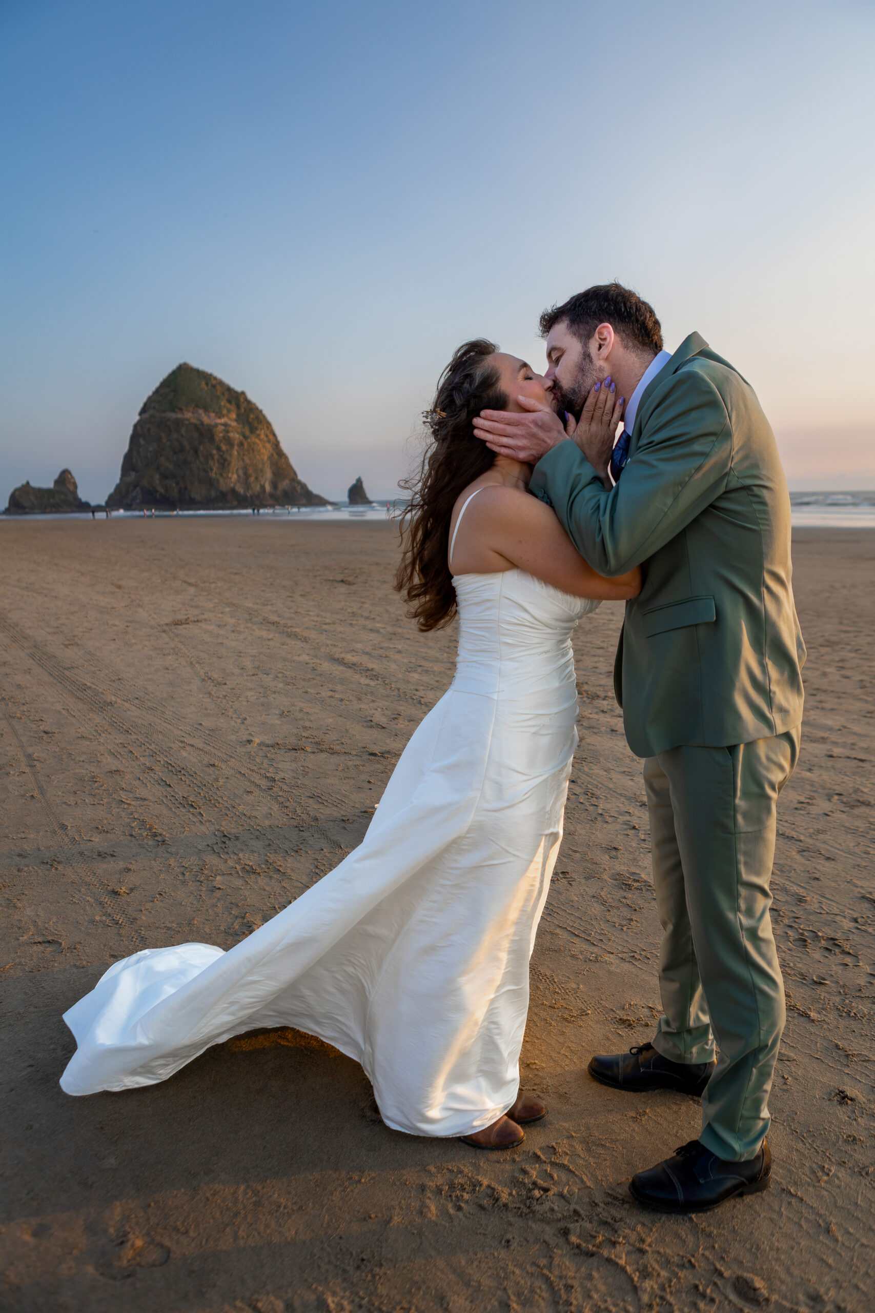 couple exchanging first kiss in front of haystack rock in cannon beach, oregon