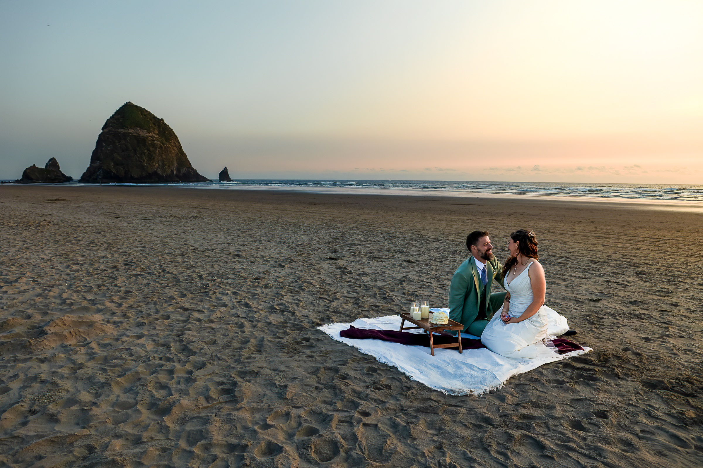 enjoying a picnic celebration in front of Haystack rock during this Oregon coast elopement