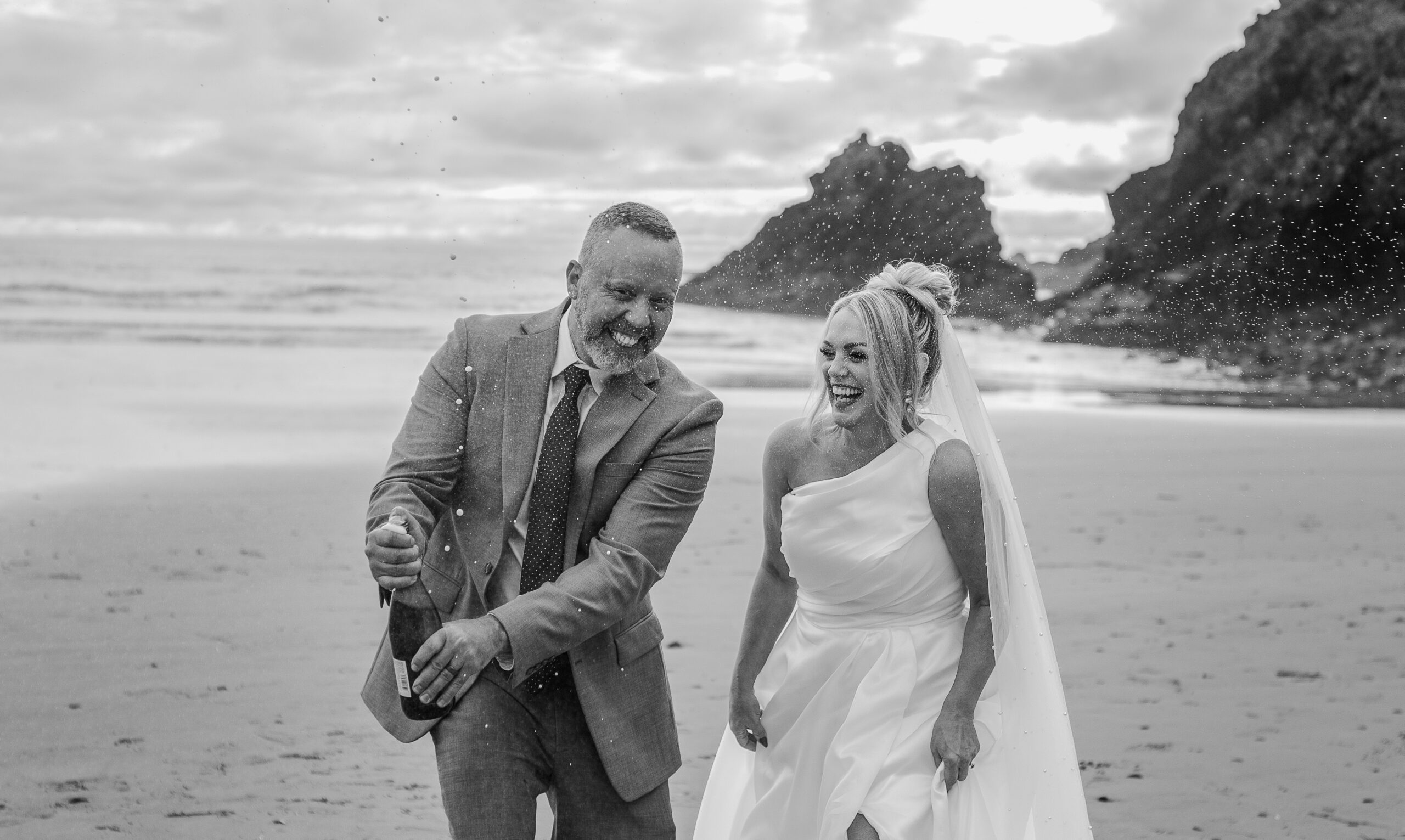 Playful champagne pop during sunset elopement on the Oregon Coast