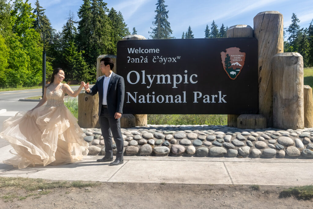 couple having first dance in bridal attire in front of olympic national park sign